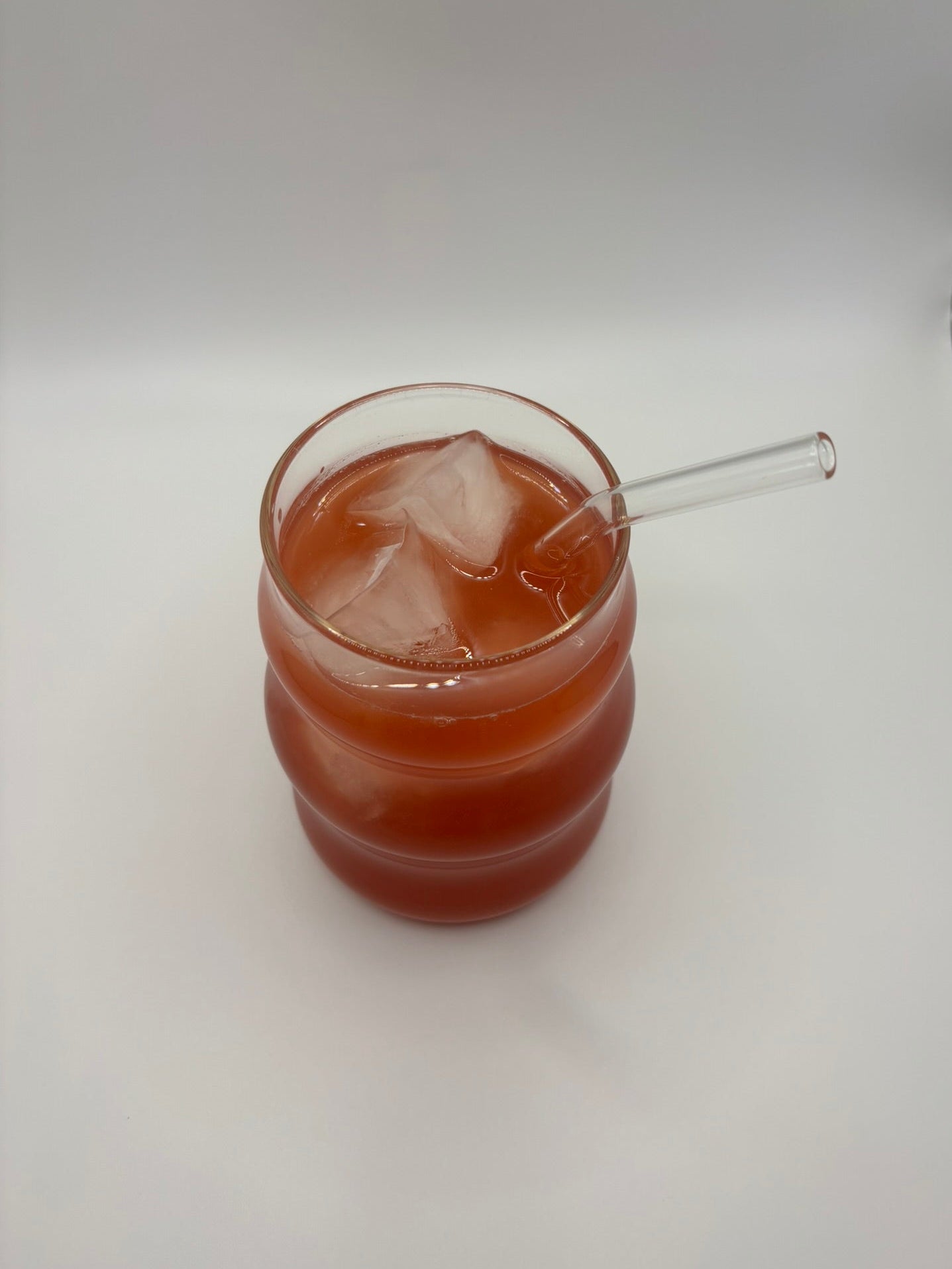 Glass of custom skin glow blend with a straw on a white surface