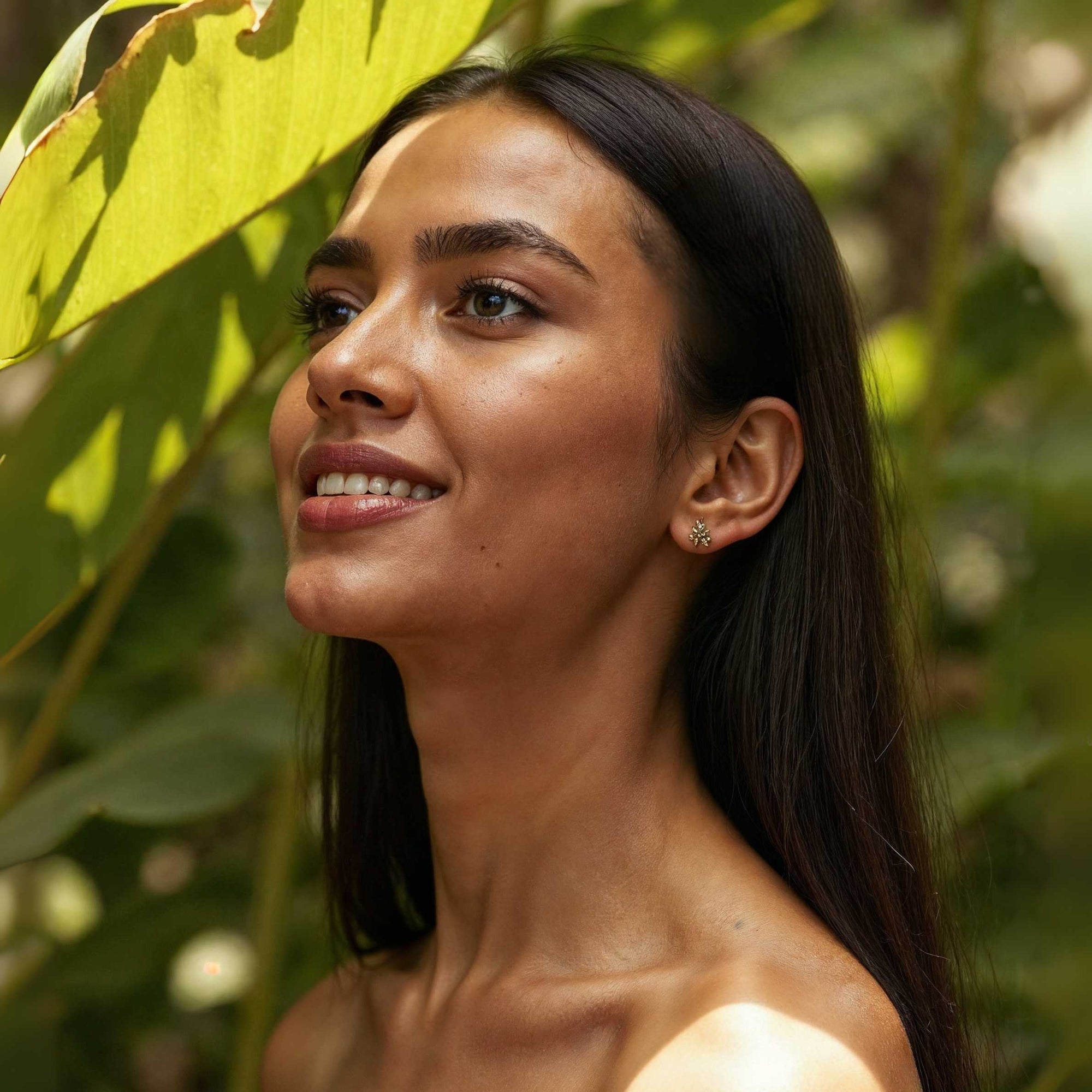 Woman with a radiant smile and glowing skin surrounded by green leaves