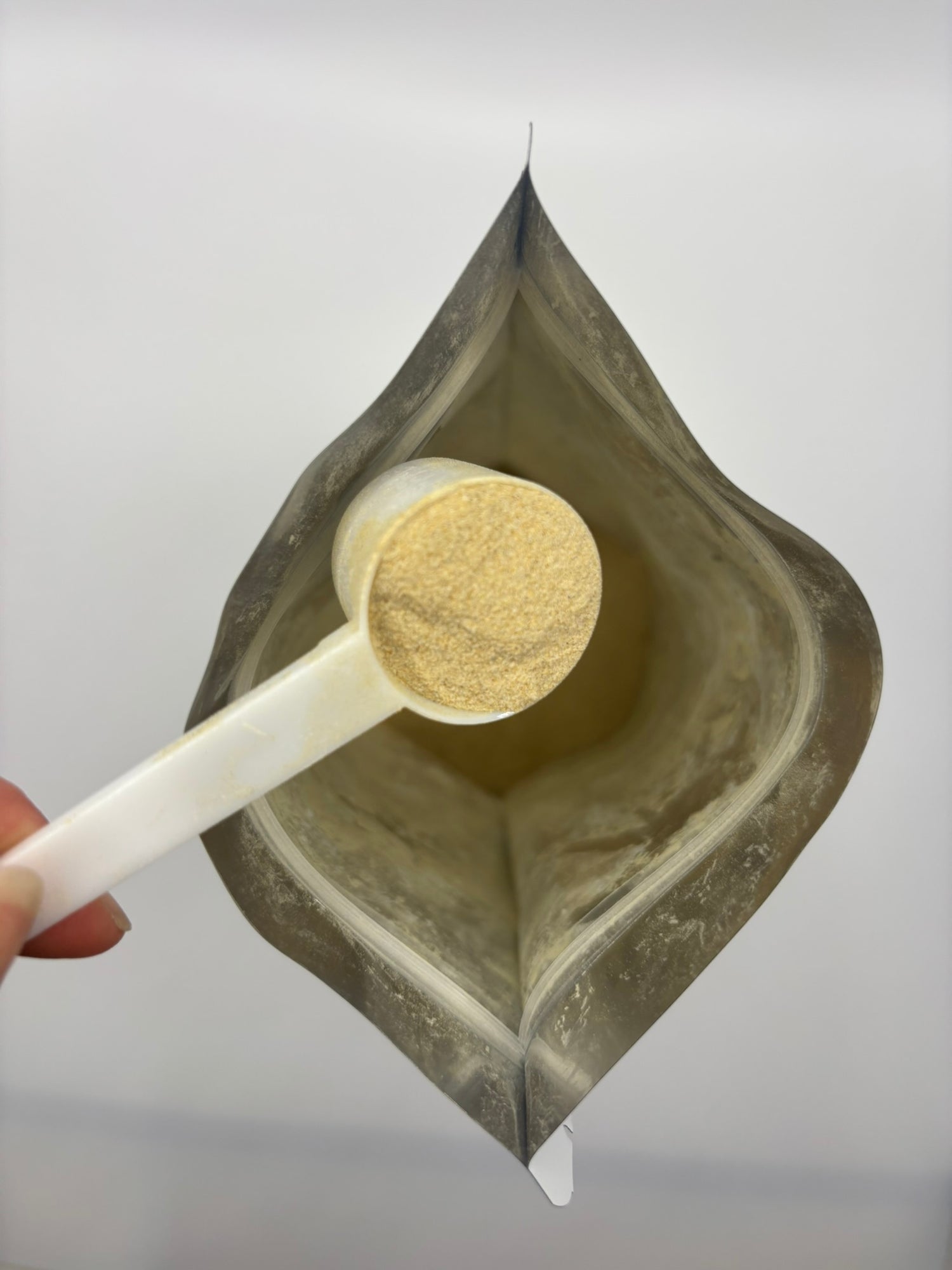 Custom gut health blend pouch with a scoop of the powder held above it against a white background