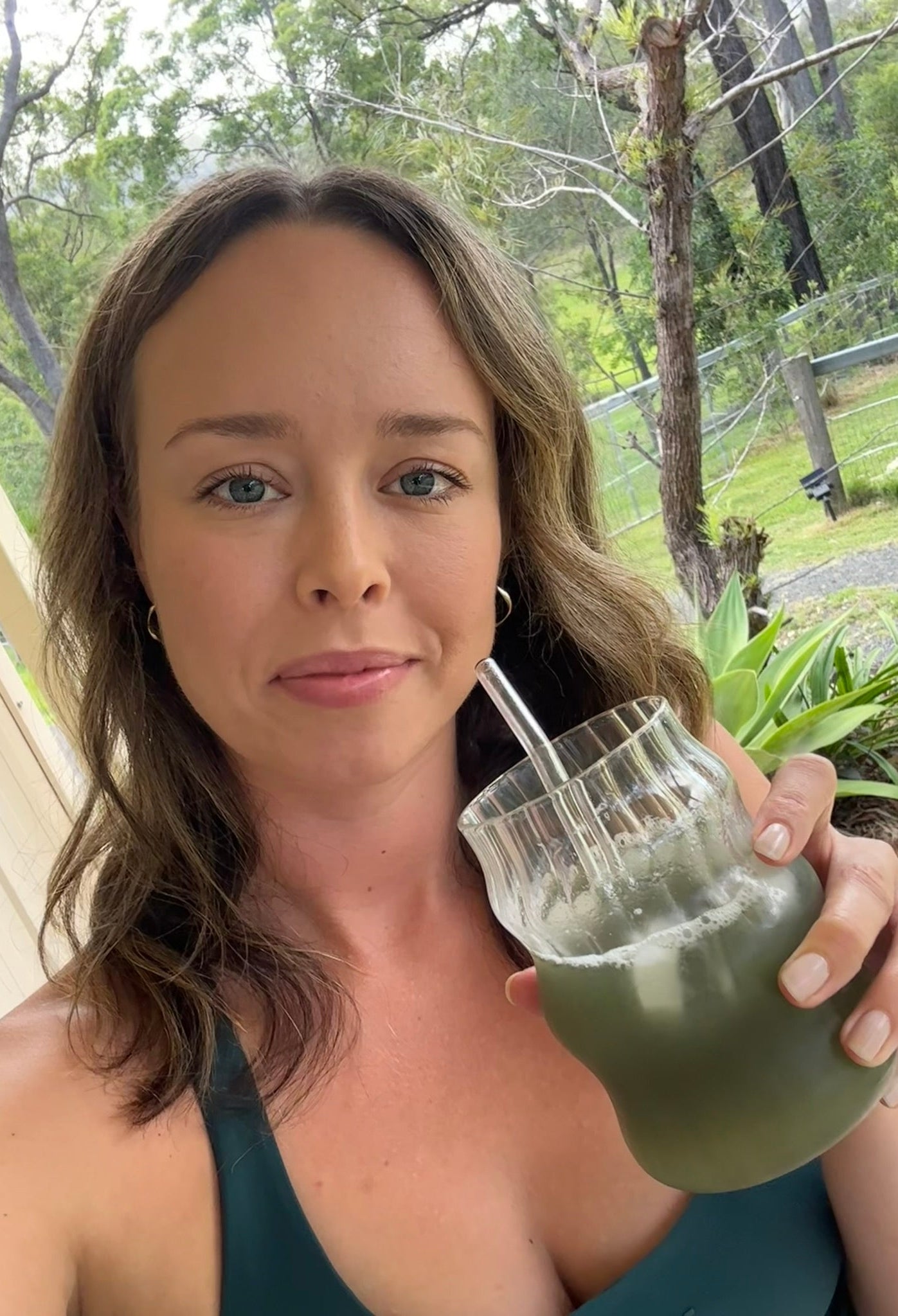 Kate Taylor, founder, holding custom gut health blend drink with a straw outdoors