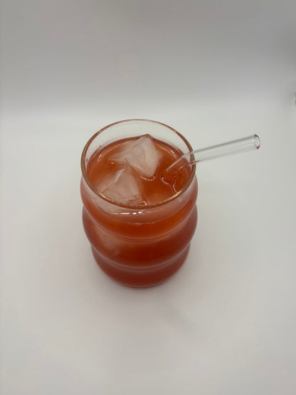 Glass of custom skin glow blend with a straw on a white surface